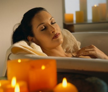 Женщина раслаябляется в ванне со свечками